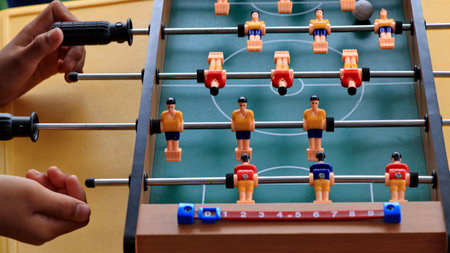 close up of a person hands playing foosball, turning the handles on a table soccer game. Plastic...