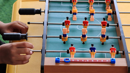 close up of a person hands playing foosball, turning the handles on a table soccer game. Plastic...