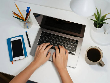 Top view of a clean minimalist desk with laptop, smartphone, coffee cup, notebooks, lamp, pencils, and plant. Perfect for concepts of remote work, freelance, productivity, online business, and study.の素材