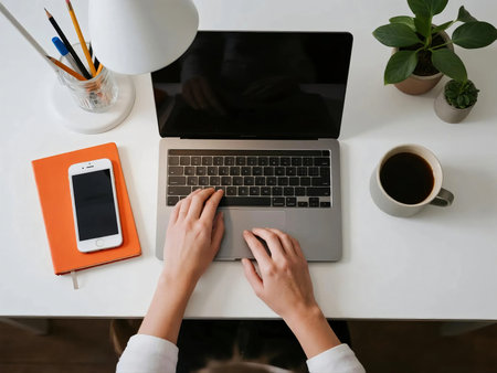 Top view of a clean minimalist desk with laptop, smartphone, coffee cup, notebooks, lamp, pencils, and plant. Perfect for concepts of remote work, freelance, productivity, online business, and study.の素材