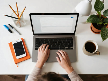 Top view of a clean minimalist desk with laptop, smartphone, coffee cup, notebooks, lamp, pencils, and plant. Perfect for concepts of remote work, freelance, productivity, online business, and study.の素材