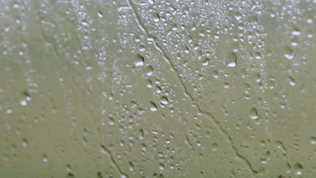 View of raindrops on a glass window forming natural textures and abstract patterns, symbolizing...
