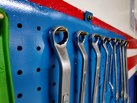 Wrenches hanging neatly on a blue pegboard in a workshop, showcasing organization and readiness for automotive repairs in a professional setting.の写真素材