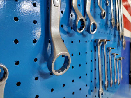 Wrenches hanging neatly on a blue pegboard in a workshop, showcasing organization and readiness for automotive repairs in a professional setting.の写真素材