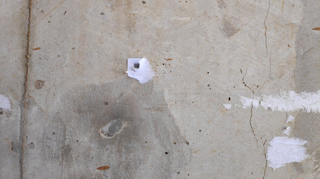 Concrete wall shows remnants of torn posters in urban environment, revealing texture and decay with a sense of history and neglect.の写真素材
