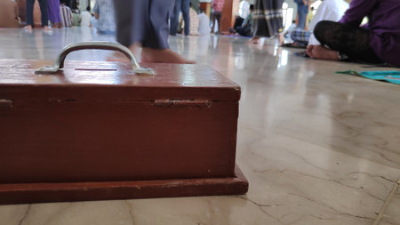 Wooden box sits closed on a tiled floor with a metal handle, showing simple construction and utility in a rustic setting.の写真素材