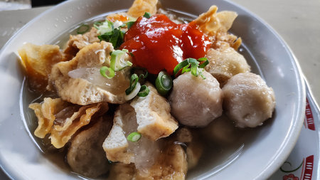 Bakso a traditional indonesian dish, served in a white bowl with spicy red sauce, showcasing the rich culinary heritage of indonesia.の写真素材