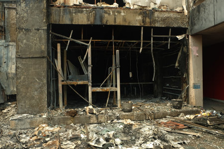 Burnt building shows aftermath of fire damage with debris and charred remains in urban setting, reflecting destruction and loss.の写真素材