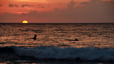 Person wading in ocean during sunset with golden light reflecting on water creating a peaceful and serene scene. evoking a sense of peace and tranquility.の写真素材
