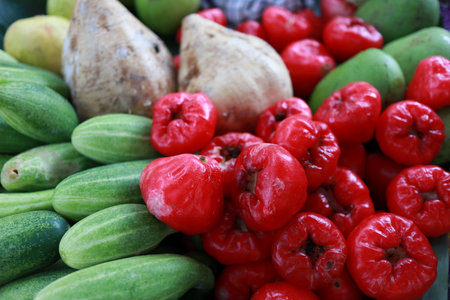 Fresh cucumbers, rose apples, and jicama, guava arranged at an outdoor market stall create a vibrant and colorful display of tropical produce, showcasing the abundance of local agriculture.の写真素材