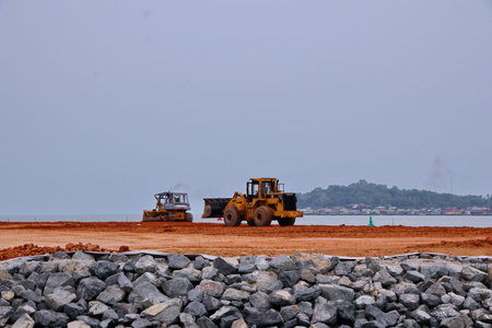 yellow tractor and heavy construction machinery transport equipment across a rural field, across a...