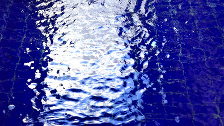 Vibrant blue water with rippling motion and bright reflections creates a dynamic abstract background inspired by swimming pool surfaces.の写真素材