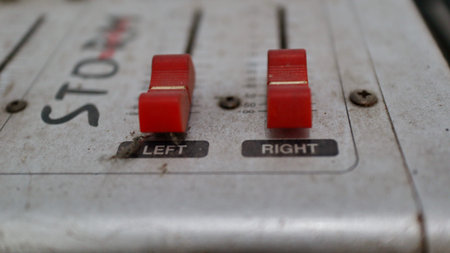 View of a vintage and dusty analog audio mixer panel with two red fader controls labeled LEFT and...