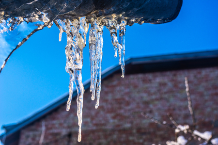 Icicles hanging from the roof close upの写真素材