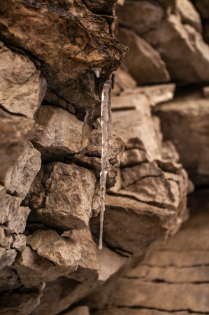 Icicle hanging from a stone close upの写真素材