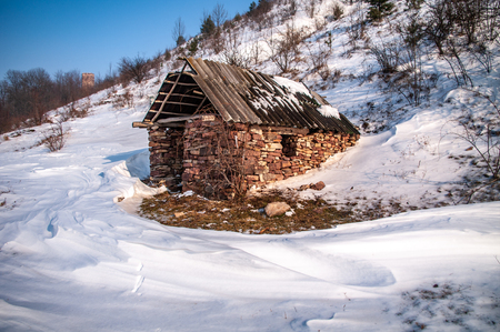 Ruined stone house on the river bank in winterの写真素材