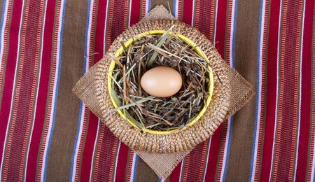 easter basket with egg on a striped tablecloth の写真素材