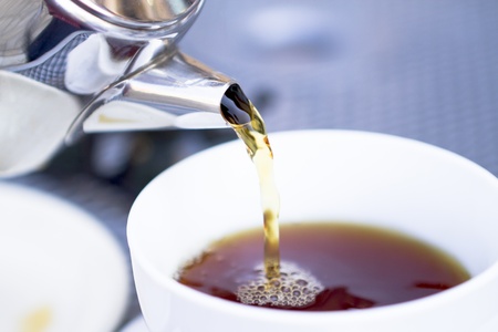 Pouring hot black tea from restaurant style cattle. Selective focused on kettle and poured tea.の写真素材