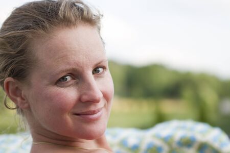 Beautiful Blond Turkish lady looking at the camera. Green blurry foliage at the background. No Make-upの写真素材