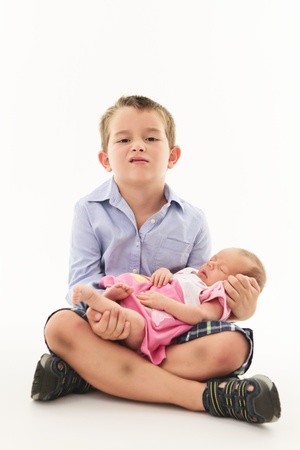 Mischievous boy holding newborn baby sister.の写真素材