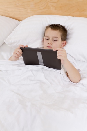 First grade kid completing his bed time reading on his tablet.の写真素材