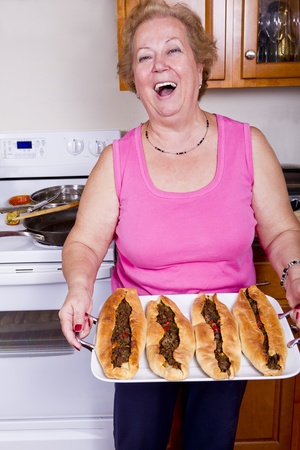 Happy older lady showing freshly cooked Turkish Pides proudly after take them out from the Owen.の写真素材