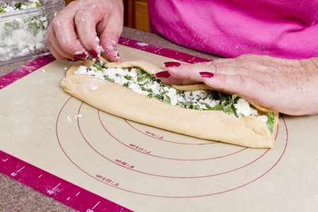 Older lady hands are wrapping Turkish feta cheese Pide pockets.の写真素材