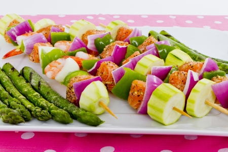 Salmon cubes and Shrimp complimented with vegetables on skewers. Ready to cook. Red onions, zucchini, green peppers and asparagus.の写真素材