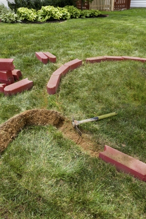 Laying brick edgers around the house for easy trimming and cutting the grass.の写真素材