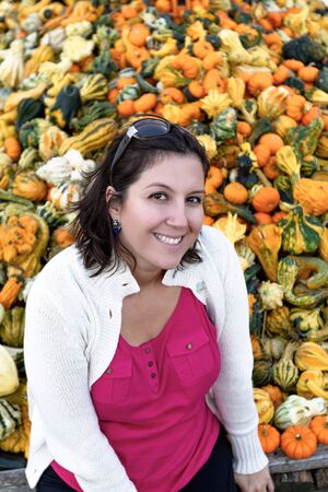 Woman infront of diffrent colors of ornamental pumpkins with fall clothings.の写真素材