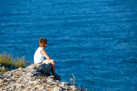 Young kid watching the Black Sea, He is high on the rocks.の写真素材