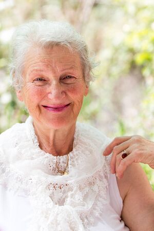 Grandmother still looking at you positively with her white hair and complimenting nice clothing.の写真素材