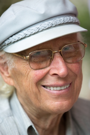 Senior man smiling at camera with his hat and glasses の写真素材