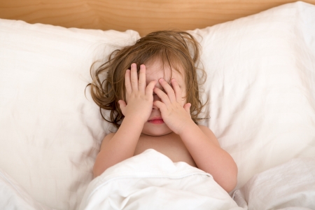 Toddler Girl closing her eyes in the bed, perhaps she is seeing bad dreams.の写真素材