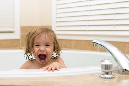 Toddler girl laughing cheerfully her moth open from bath tub  Teethingの写真素材