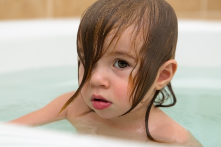 Big eye toddler girl giving thoughtful expression, perhaps attidue  She has wet hair in the bath tub の写真素材