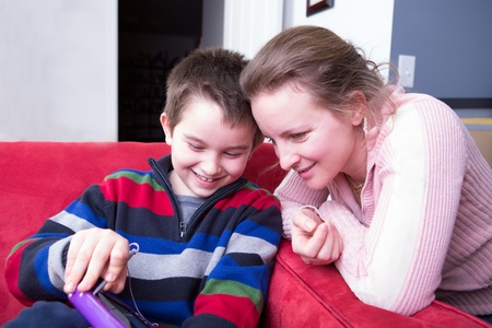 Mother and her son looking at the tablet. He is showing his creativity happily while she is showing...