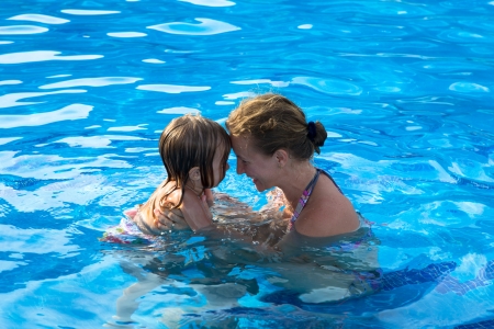Mother and doughter head to head having passionate great time in the swimming pool.の写真素材