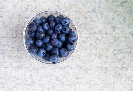 Blueberries in a plastic cup shot from above on a concrete surfaceの写真素材