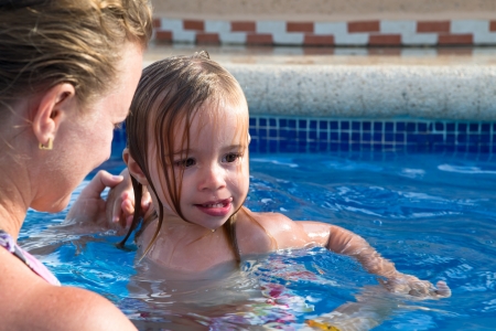 Mother and Daughter playful in the pool, daughter came out from the water hair all wetの写真素材