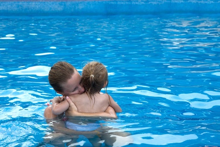 Mother and daughter cuddling in the pool with copy space on the rightの写真素材