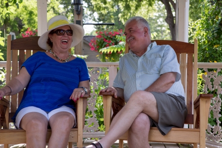 Retired couple having fun conversations. Woman is laughing while her husband happily looking at herの写真素材