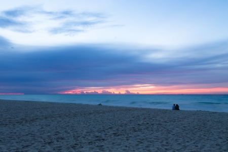Romantic couple watching the waves and sunrise at the beach. Cozumel Mexicoの写真素材