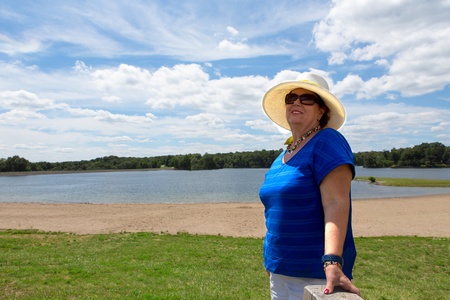 Matured woman standing on a Greenfield over the blue sky backgroundの写真素材