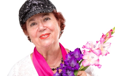 Senior lady smiling to camera happily with her black stylish hat and holding gladiolus flowers. Isolated on white.の写真素材