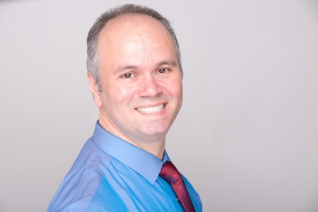 A middle age office worker smiling to the camera with his blue shirt and red tie.の写真素材