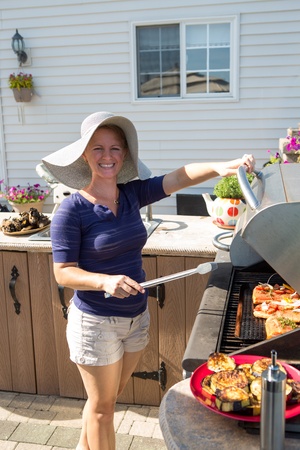 Young lady cooking salmon steaks at outside kitchen barbecueの写真素材