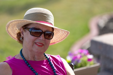 Woman with her straw hat looking at camera behind her sunglasses.の写真素材