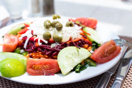 Closeup view of a plate of fresh mixed salads and vegetables with tomato, cucumber and lemon in the foregroundの写真素材