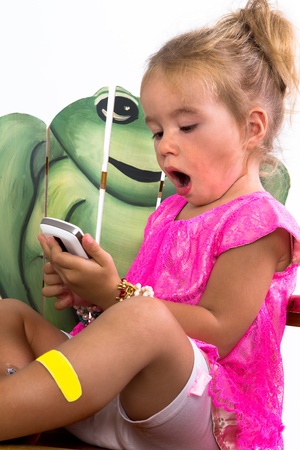 child playing with smartphone with a frog in the backgroundの写真素材